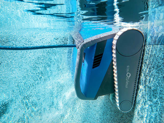 A Maytronics Dolphin M 600 sitting underwater on the pool floor